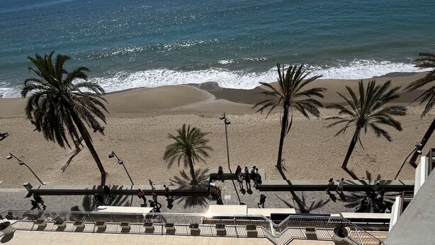 Un espace piscine comprenant deux piscines, une plage bordée de palmiers et une vue sur l’océan.
