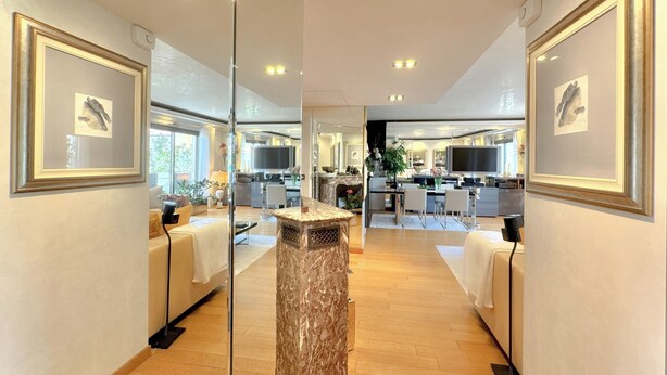 A modern hotel lobby with a marble reception desk, framed artwork on the walls, and a view into the dining area. - Luxury 2-Bedroom Apartment - Rue d'Antibes, Cannes (Cannes)