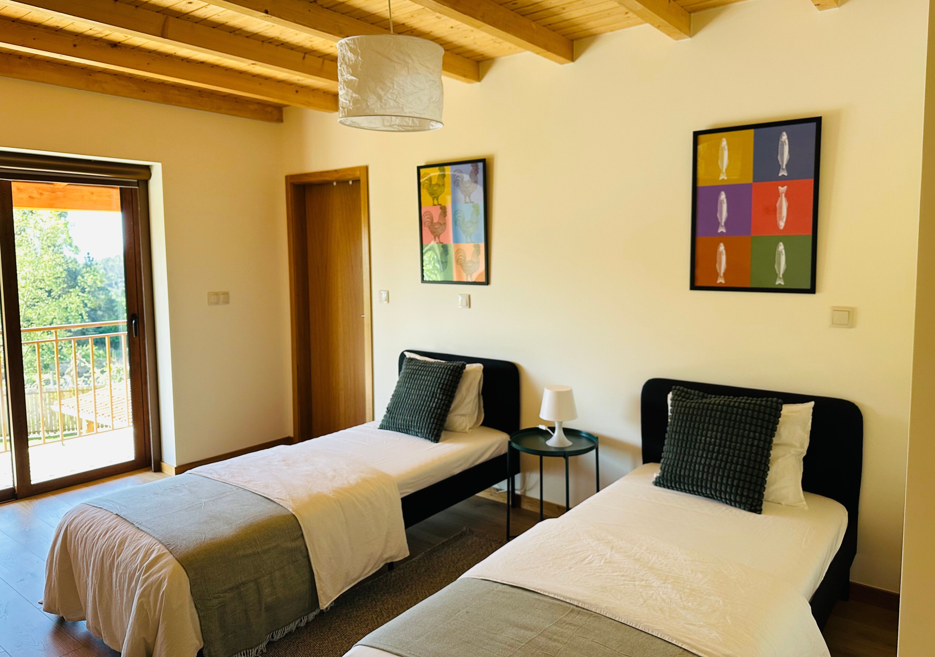 A room with two beds, a small table, and a door leading to a balcony.