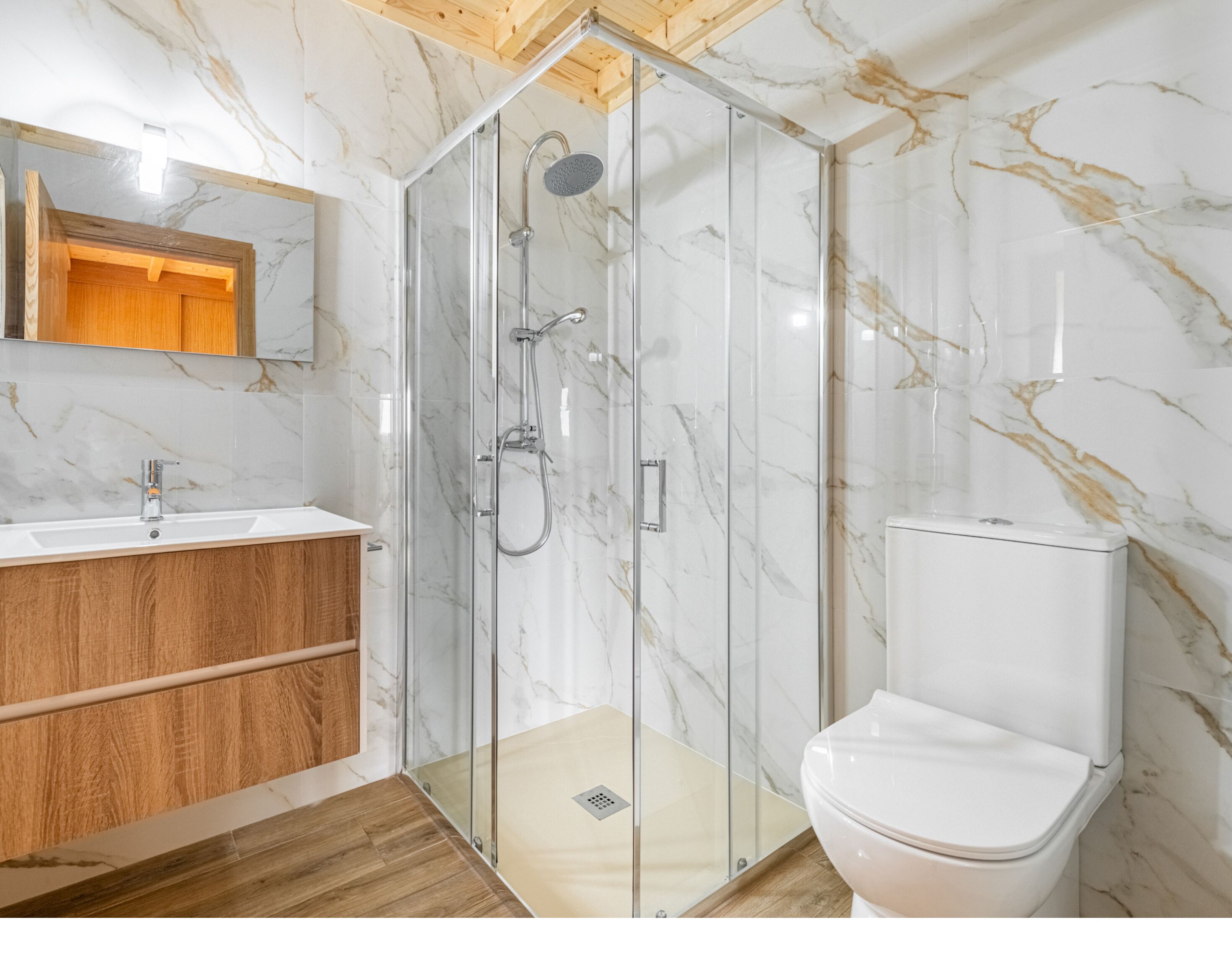A bathroom with a glass-enclosed shower, a wooden vanity, and a white toilet.