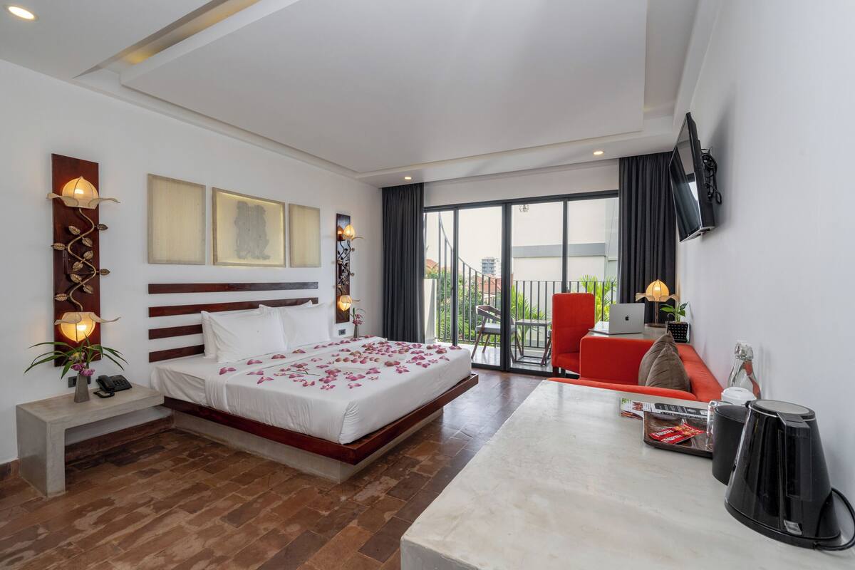 Une chambre d’hôtel moderne dotée d’un grand lit, d’un bureau, d’une chaise, d’une télévision et d’un balcon avec vue.