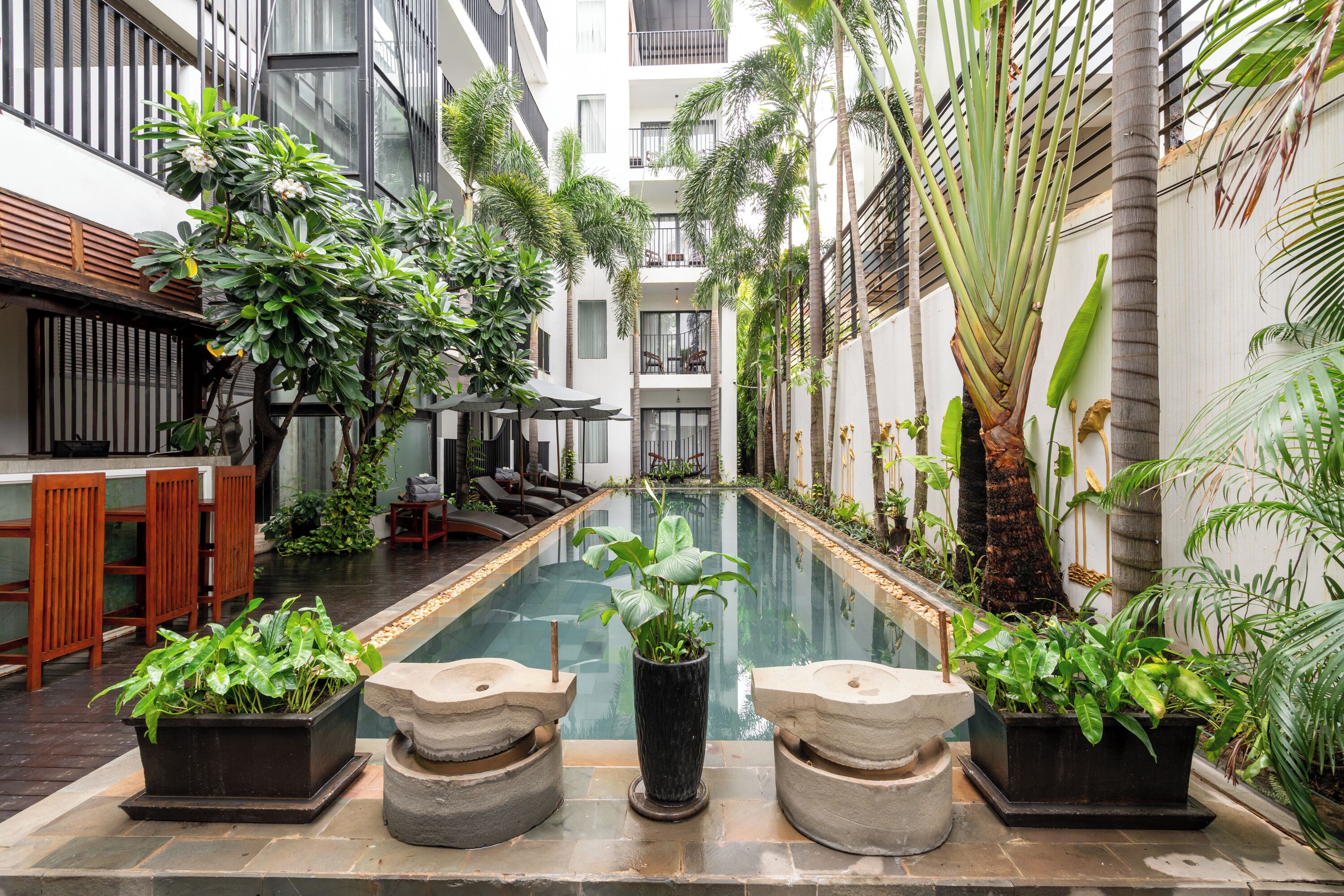 Un área de piscina con bar, asientos y plantas en macetas.