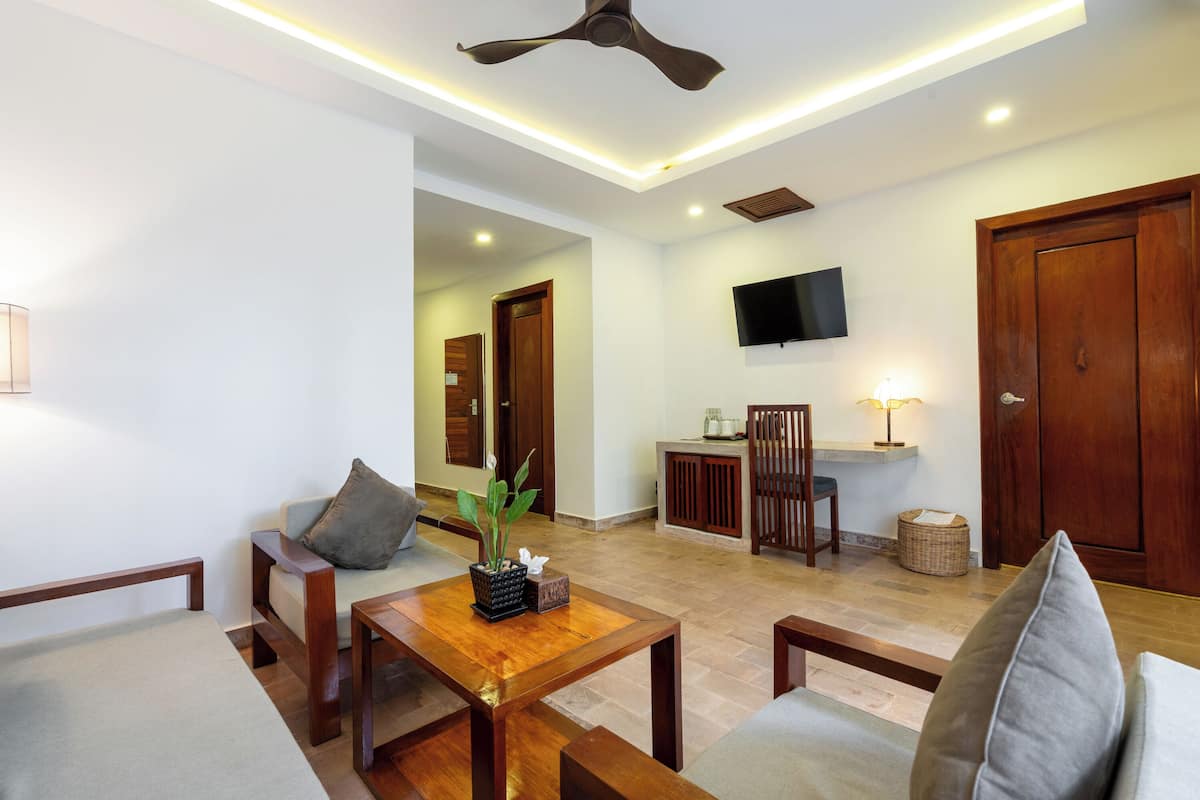Un salon moderne doté d’un ventilateur de plafond, d’un téléviseur à écran plat fixé au mur et d’un meuble en bois.