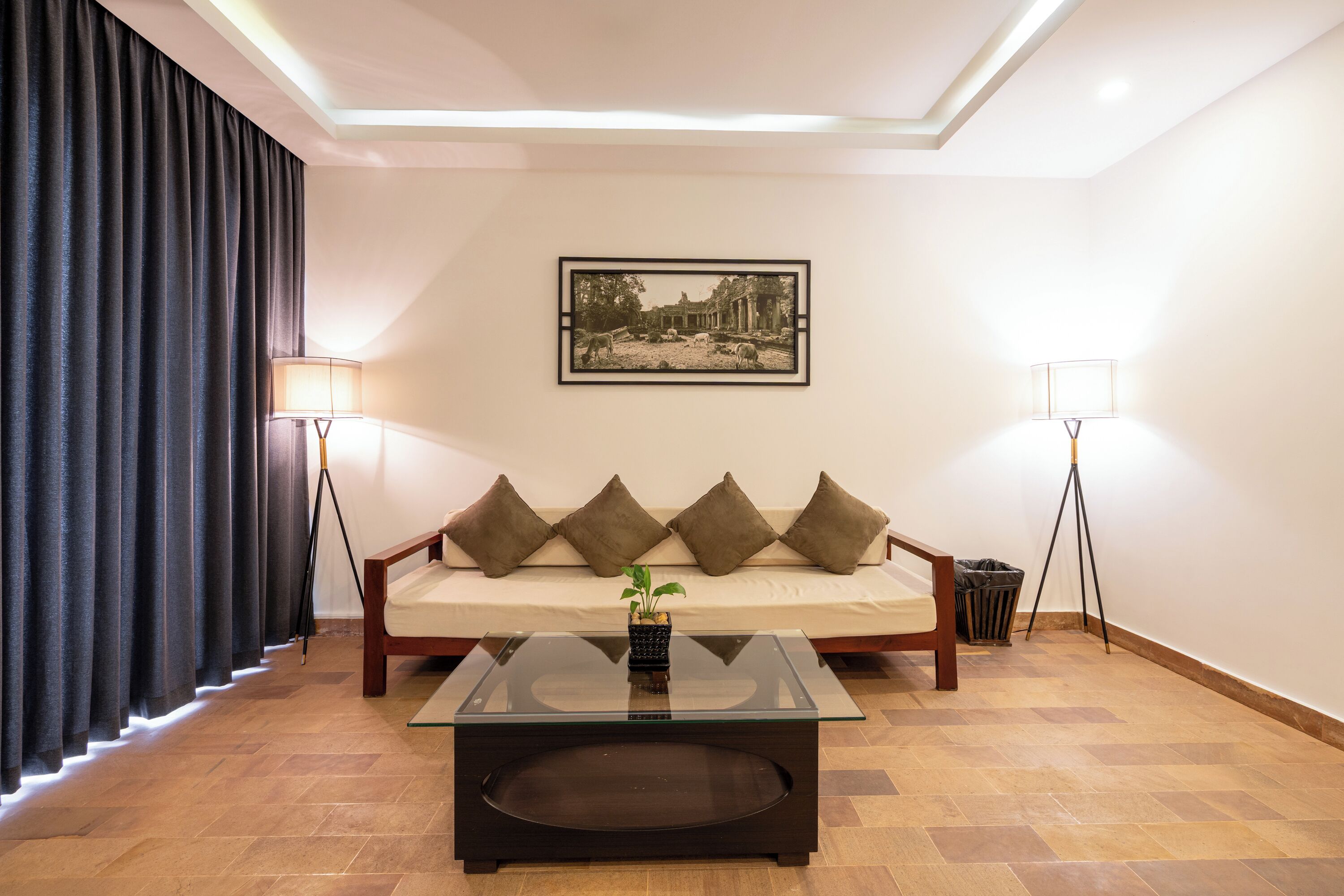 Ein modernes Wohnzimmer mit einer Couch, einem Glastisch und zwei Stehlampen.