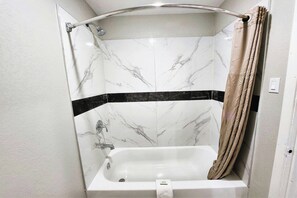 Une salle de bain avec une douche, une baignoire et un porte-serviettes.