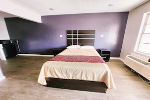 Un dormitorio con cama, mesitas de noche, un calentador y una ventana.