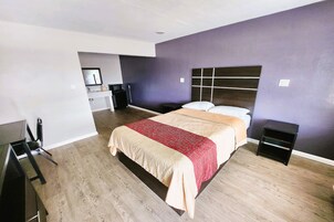 Un dormitorio con cama, mesitas de noche, escritorio y una silla.