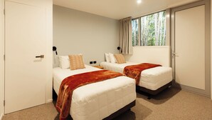 Una habitación de hotel con dos camas, un ventanal con cortinas y una puerta.