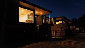 Una casa moderna con un amplio ventanal y una escalera que lleva a un nivel superior.