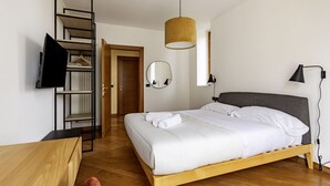 Une chambre à coucher comprenant un lit, un bureau en bois, un miroir, un luminaire suspendu et une armoire avec un miroir.