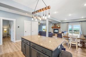 A modern kitchen with granite countertops, a built-in island, and a dining area with a wooden table and chairs.