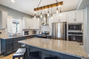 A modern kitchen with a granite countertop, stainless steel appliances, and pendant lighting.