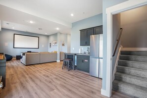 A modern kitchen with grey cabinets, a stainless steel refrigerator, and a built-in stove.