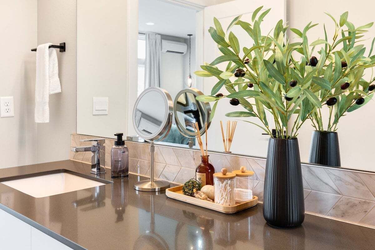A bathroom with a mirror, sink, and decorative plants.