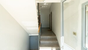 A narrow stairway with a handrail, a light fixture at the top, and a door on the right.