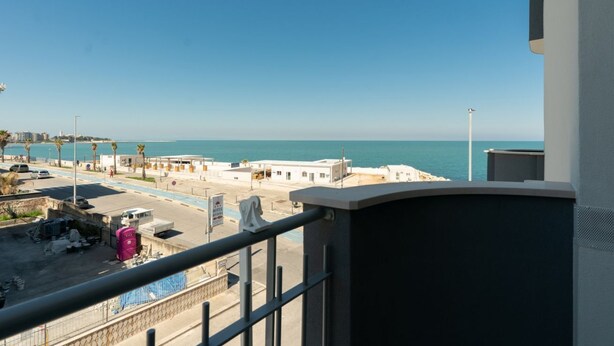 A coastal view with buildings, a road, and a clear sky.