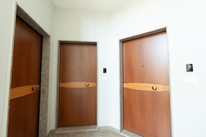 Three wooden doors with a central door flanked by two others, each with a wooden handle and a small circular lock.