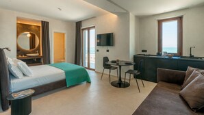 A modern hotel room with a bed, a desk, a TV, and a view of the sea. - GuestHost –La Rosa dei Venti, Borea Apt by the sea (Trani)