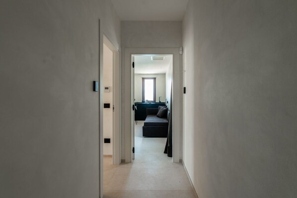 A narrow hallway leading to a living area with a sofa and a window.