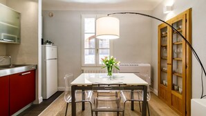Een moderne keuken met een eettafel, stoelen, een koelkast en een kast met glazen deuren.