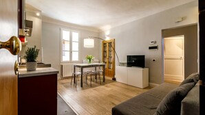 Een compacte leefruimte met een kitchenette, een eethoek en een slaapbank.