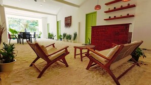 Een ruime woonkamer met een hoge plafond, een open haard en een eettafel met stoelen.