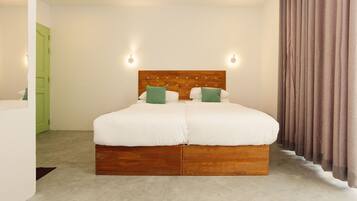 A double bed with a wooden headboard, two green pillows, and a light-colored carpet.