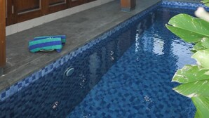 Zona de piscina exterior moderna amb sòl de rajola i aigua de color blau clar.