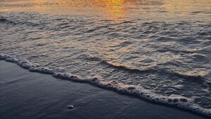 Un coucher de soleil sur une mer calme aux vagues douces.
