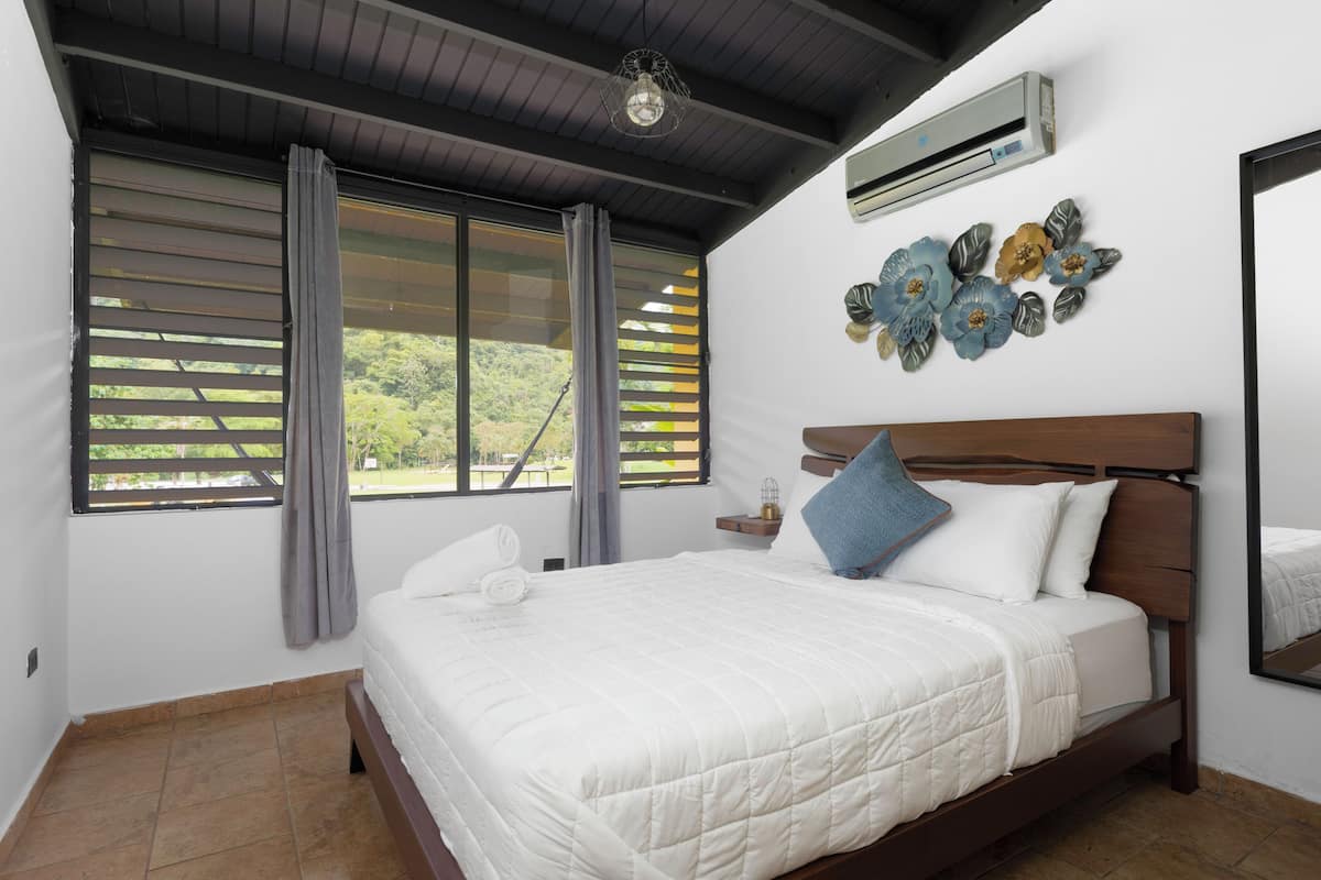 Ein Schlafzimmer mit Bett, Vorhängen, einer Klimaanlage und einer Wanddekoration.