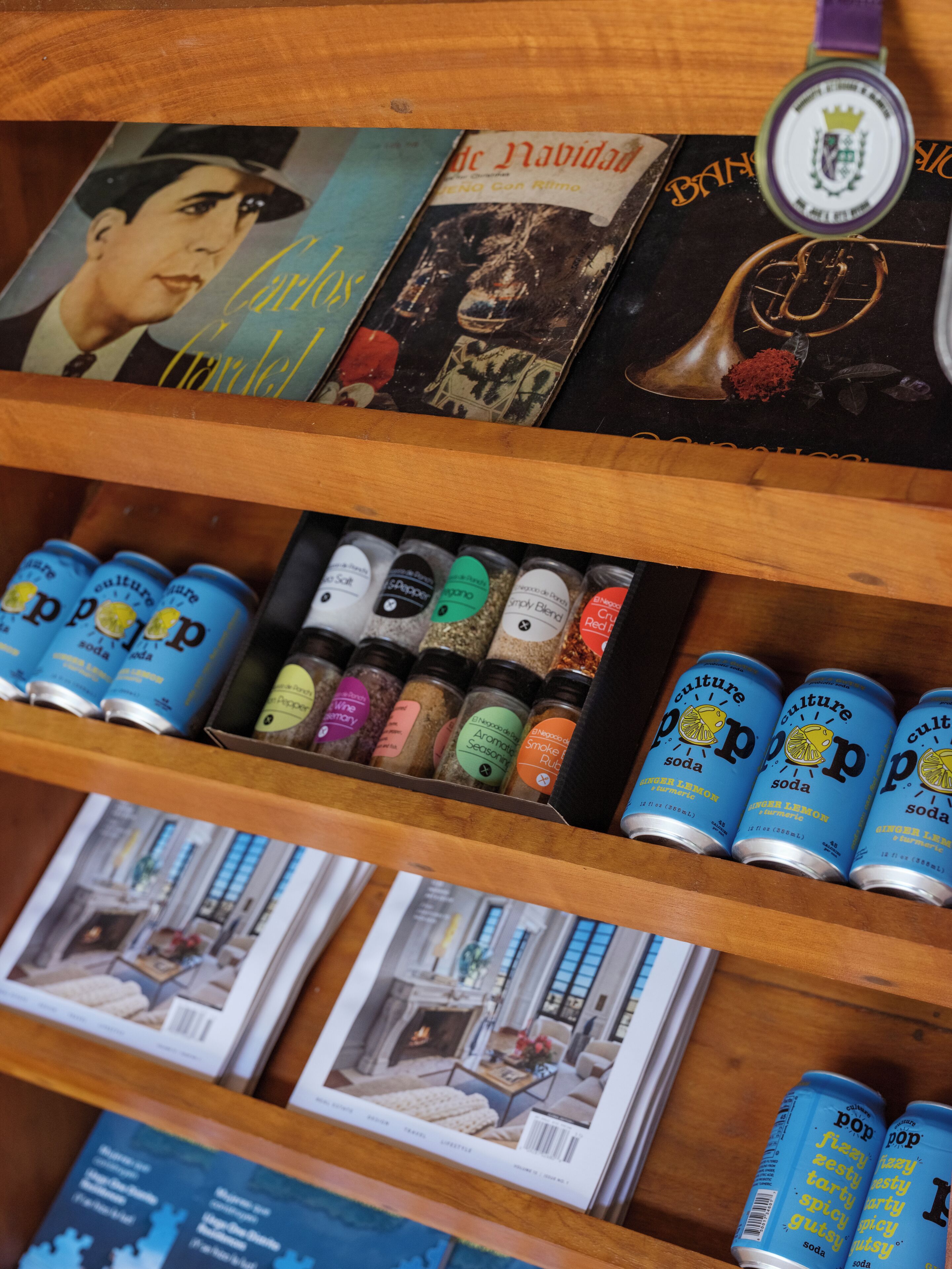 Una estantería con libros, especias y latas de refresco.