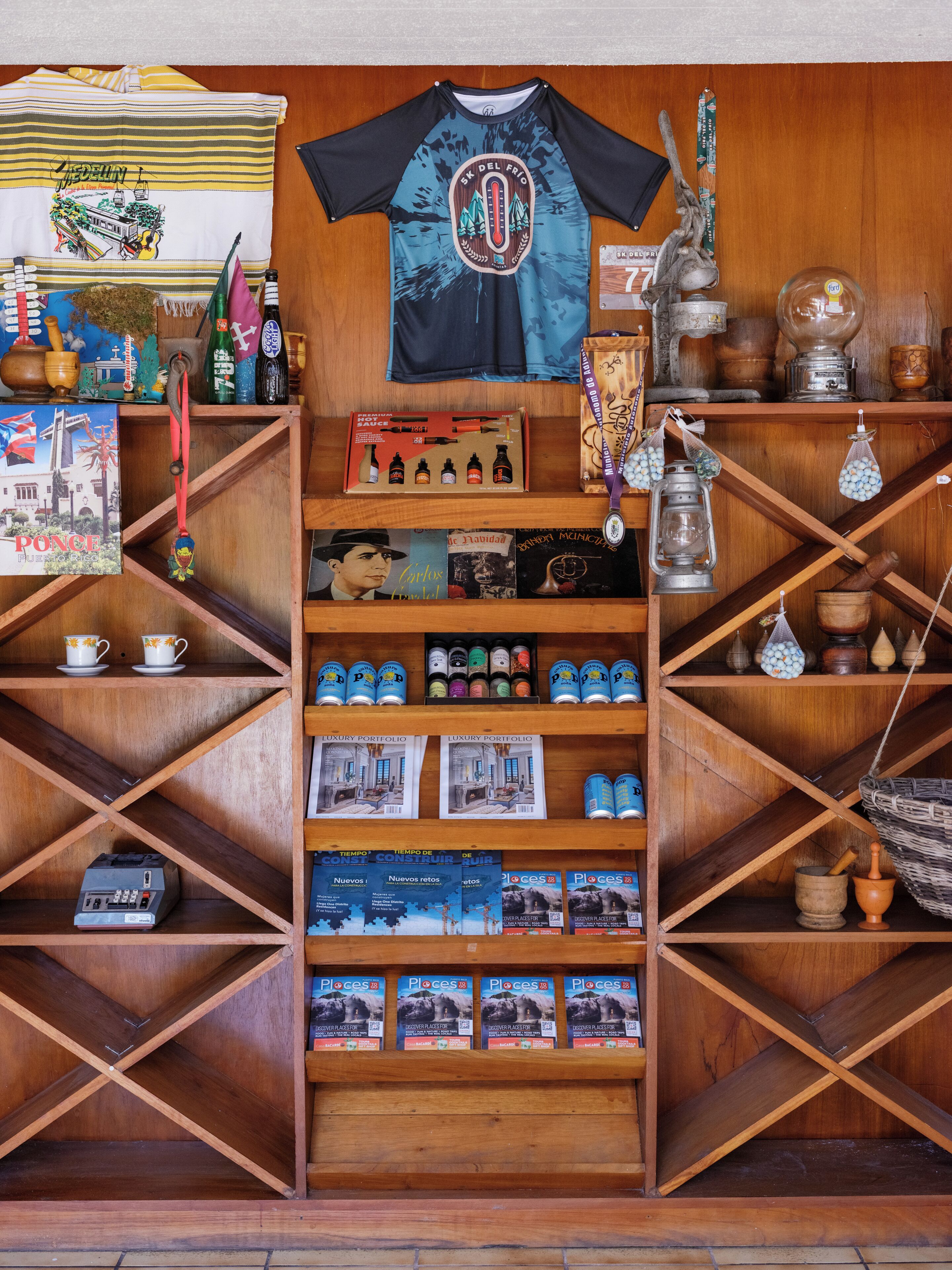 A wooden display shelf with a blue and black t-shirt, a medal, and various souvenirs.