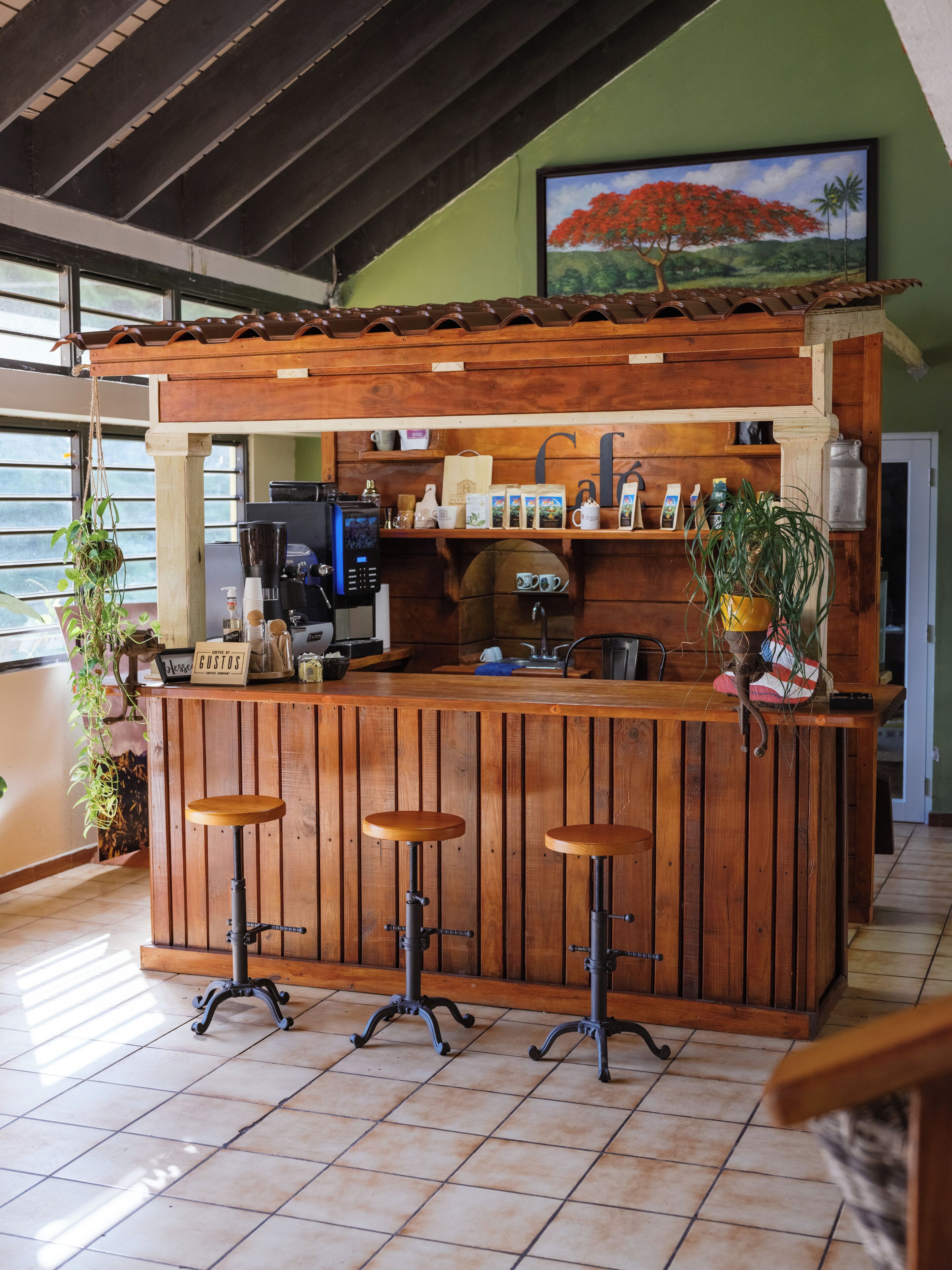 Een houten bar met krukken, een koffieapparaat en een bordje met de tekst 'Coffee Bar'.