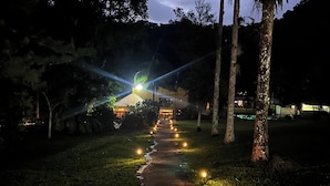 A nighttime pathway with evenly spaced lights leading to a building with a balcony.