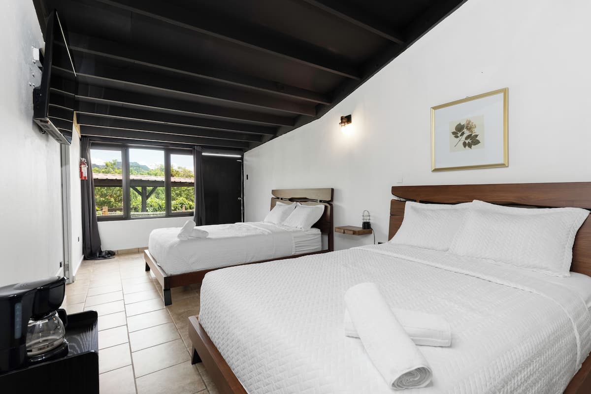 Ein Hotelzimmer mit zwei Betten, einer Kaffeemaschine, einem kleinen Tisch und einem Fenster mit Blick.