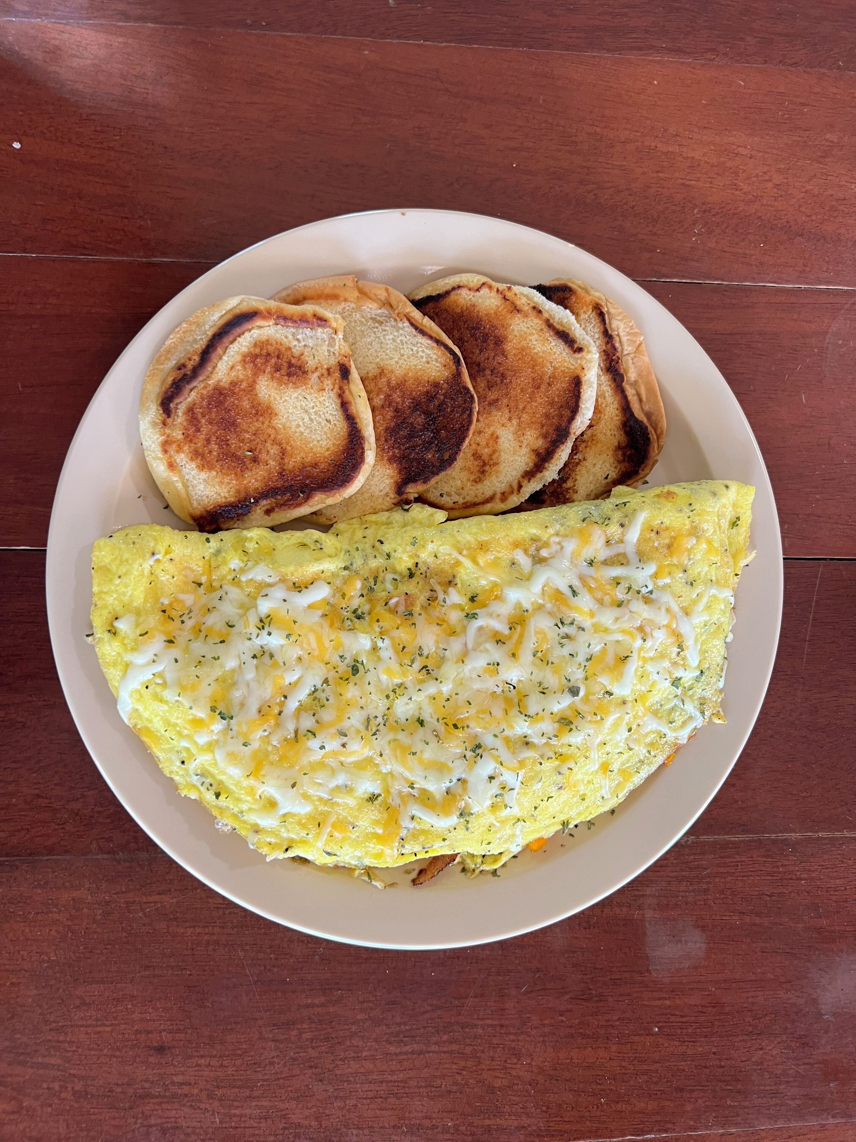 Une assiette contenant une omelette et deux tranches de pain grillé, posée sur une table en bois.