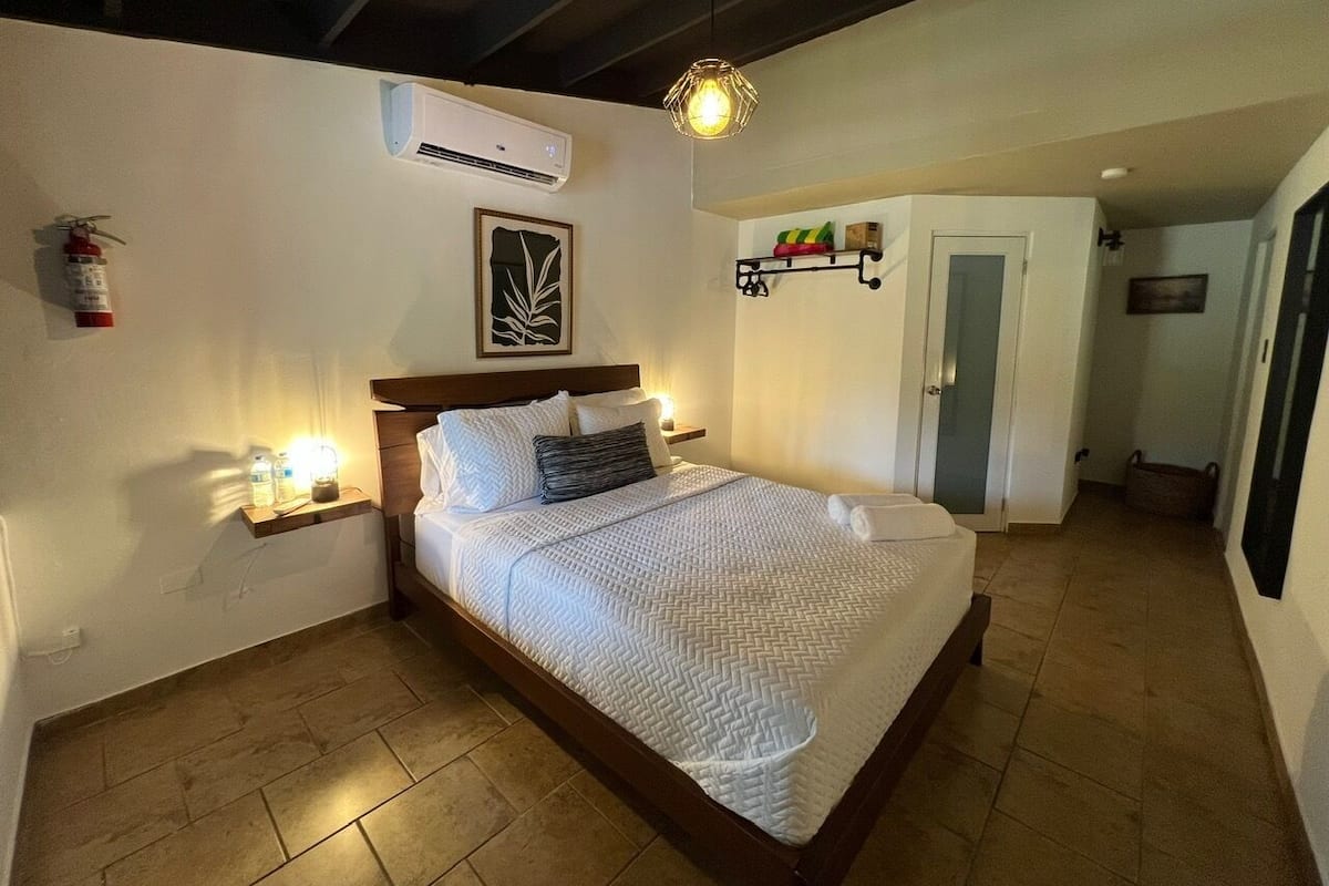 Ein Schlafzimmer mit Bett, Nachttisch, Wand-Klimaanlage und Pendelleuchte.