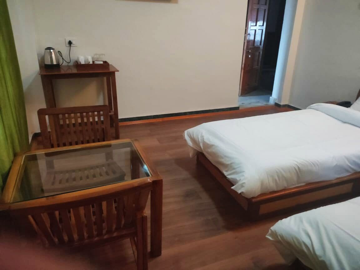 A room with a wooden bed, a glass-top table, and a chair.