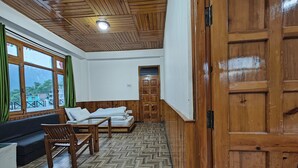 Une pièce dotée d’un parquet en bois à motifs en chevrons, d’un plafond en bois, d’une porte en bois, d’un lit avec une literie blanche, d’un banc en bois et d’une table.