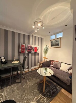 Cozy living space with a dining area and seating area, featuring a sofa, coffee table, and potted plant.