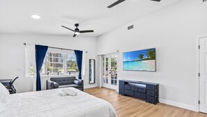 Un dormitorio con una cama grande, televisión, escritorio y balcón con vista al océano.