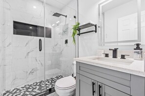 Ein modernes Badezimmer mit einer Duschkabine, einer Toilette und einem Waschbecken mit Marmorplatte.