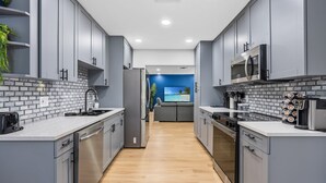 Una cocina moderna con armarios grises, un salpicadero blanco y suelo de madera.