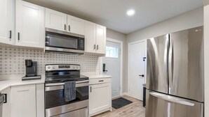 A modern kitchen with white cabinets, stainless steel appliances, and a wooden floor. - Dundee Delight 3Br2Ba sleeps 9, central Omaha, heart of historical neighborhood (Omaha)