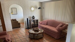 A living room with a sofa, a coffee table, a bookshelf, a lamp, and a decorative wall piece. - 3-bedroom building in enjoyable Tucson with AC, WiFi (Tucson)