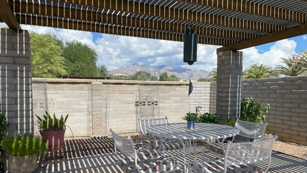 An outdoor patio with a pergola, a table with chairs, and potted plants. - 3-bedroom building in enjoyable Tucson with AC, WiFi (Tucson)
