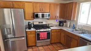 A kitchen with wooden cabinets, stainless steel appliances, a tiled floor, and a window. - 3-bedroom building in enjoyable Tucson with AC, WiFi (Tucson)