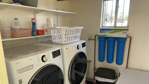 A laundry area with two LG ThinQ washing machines, a white laundry basket, a shelf with cleaning supplies, and a window with blinds. - 3-bedroom building in enjoyable Tucson with AC, WiFi (Tucson)
