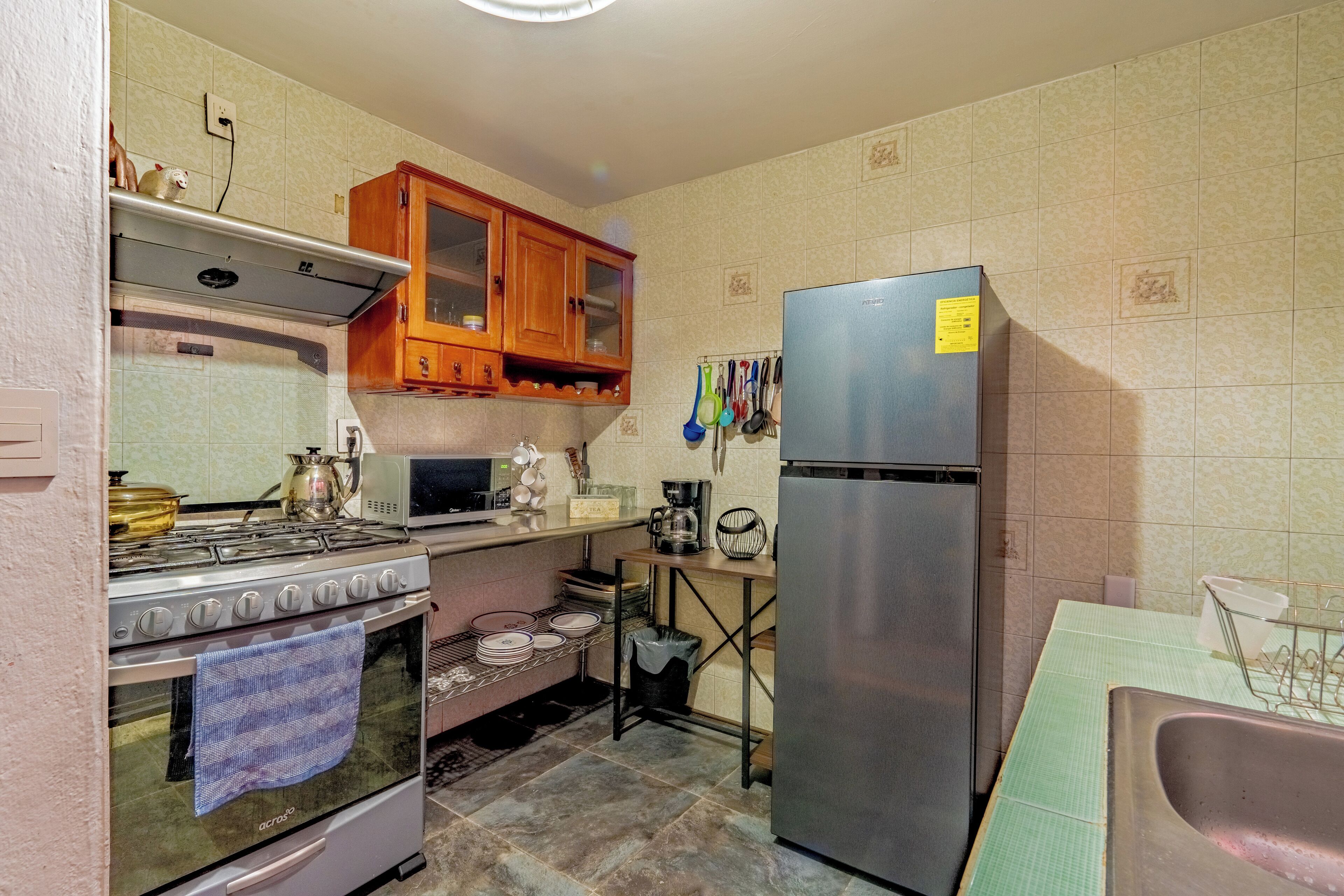 A kitchen with a stove, oven, microwave, wooden cabinets, and a refrigerator.