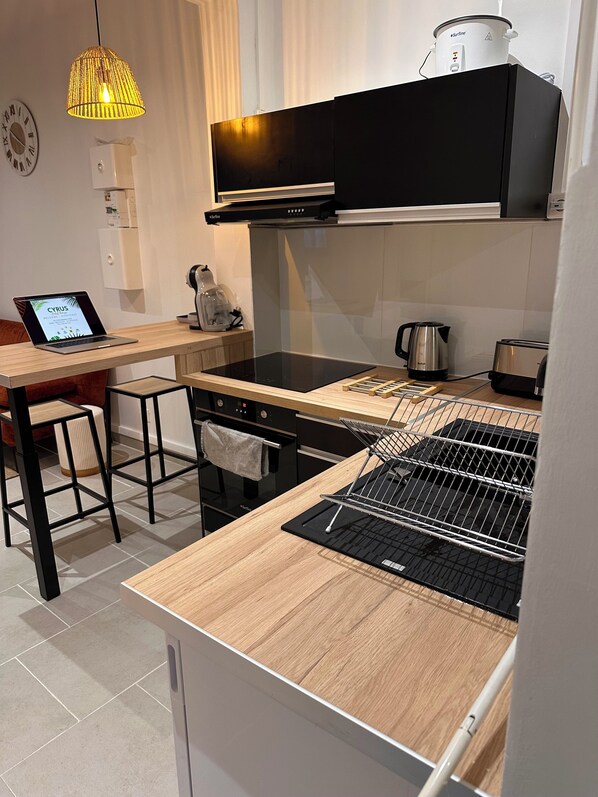 Une cuisine moderne dotée d’un plan de travail noir, d’un four encastré, d’une bouilloire et d’une machine à café.